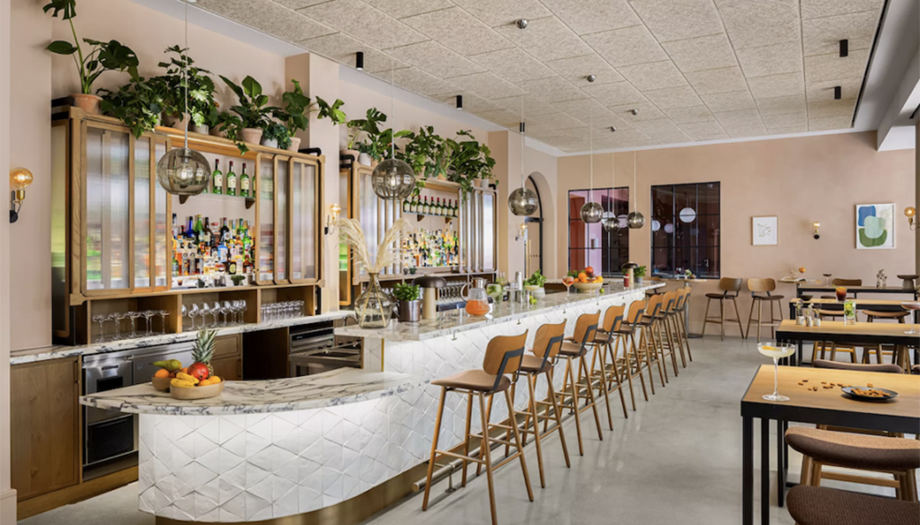 Beckett Locke's bright and airy bar features white-marble counters, wooden accents, and greenery.