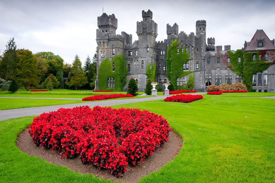 Ashford Castle with red foliage and a groomed lawn on its grounds